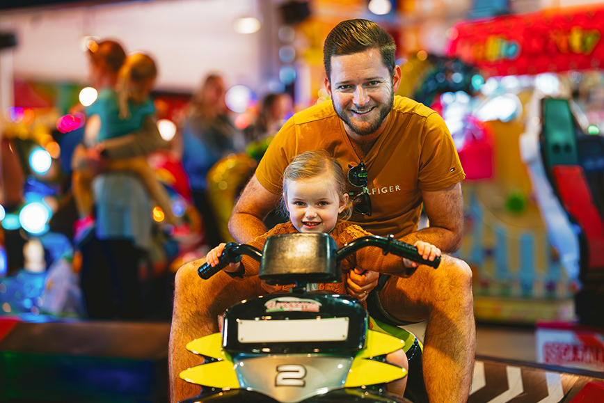 An adult and young child enjoying a ride on a disco bike
